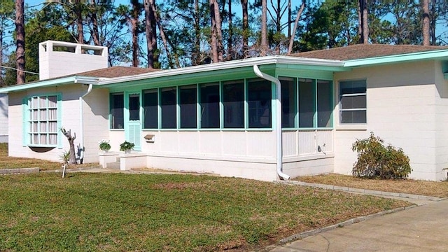 view of property exterior featuring a lawn and a sunroom