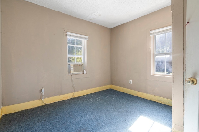 carpeted empty room with plenty of natural light, cooling unit, and a textured ceiling