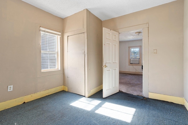 unfurnished bedroom with dark colored carpet and a textured ceiling