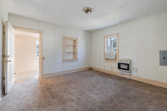 spare room with carpet flooring, built in shelves, a textured ceiling, and heating unit