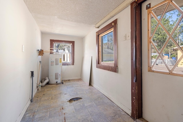 laundry room with electric water heater and a textured ceiling