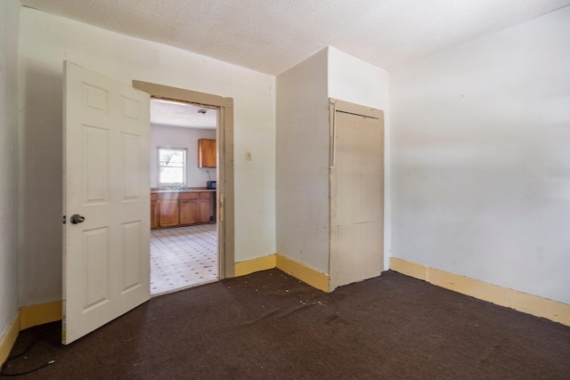 unfurnished room featuring dark colored carpet and a textured ceiling