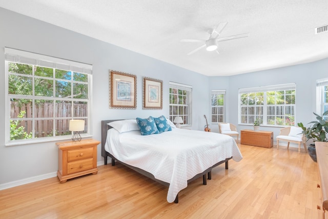 bedroom with ceiling fan, light hardwood / wood-style floors, and a textured ceiling