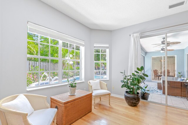 sitting room with ceiling fan, a textured ceiling, and light wood-type flooring