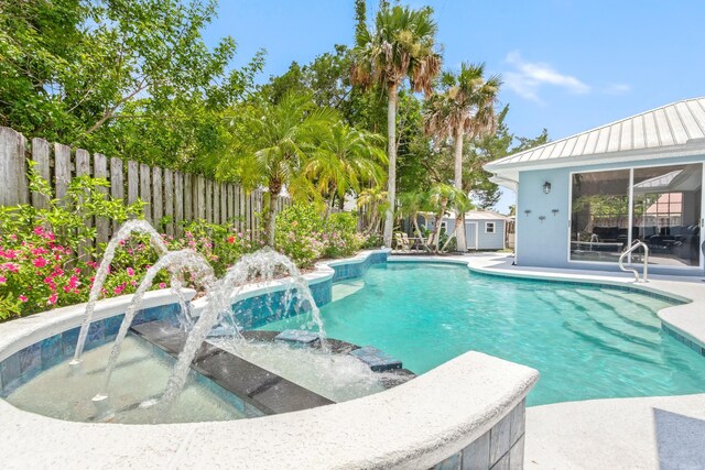 view of swimming pool with pool water feature and a storage unit