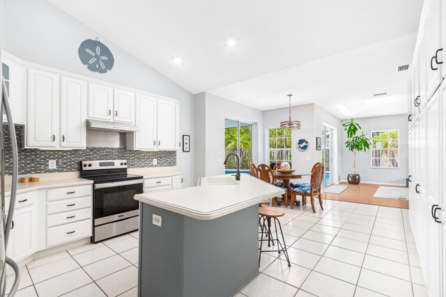 kitchen featuring light tile patterned flooring, an island with sink, sink, white cabinets, and stainless steel range with electric stovetop