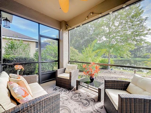 sunroom featuring ceiling fan and a water view