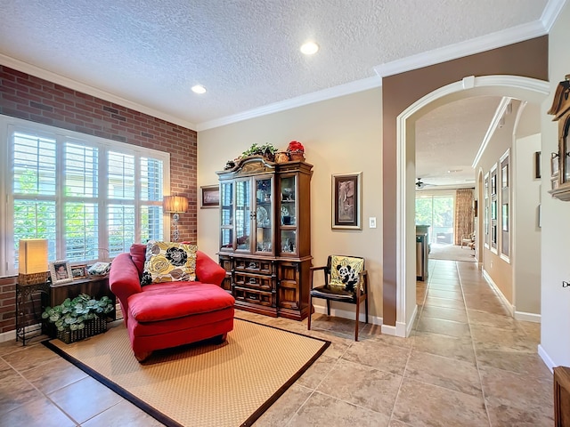 sitting room featuring crown molding, brick wall, and a textured ceiling