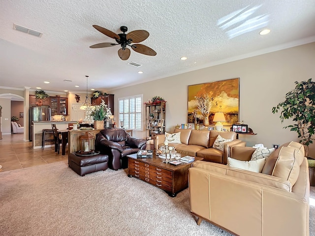 living room featuring light carpet, ceiling fan, a textured ceiling, and ornamental molding