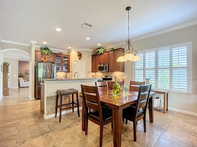 dining area featuring crown molding, sink, light tile patterned floors, and a textured ceiling