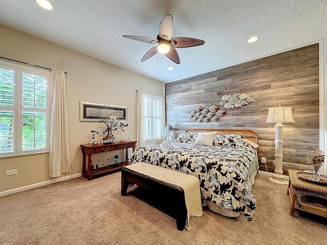 carpeted bedroom with a textured ceiling, ceiling fan, and wooden walls