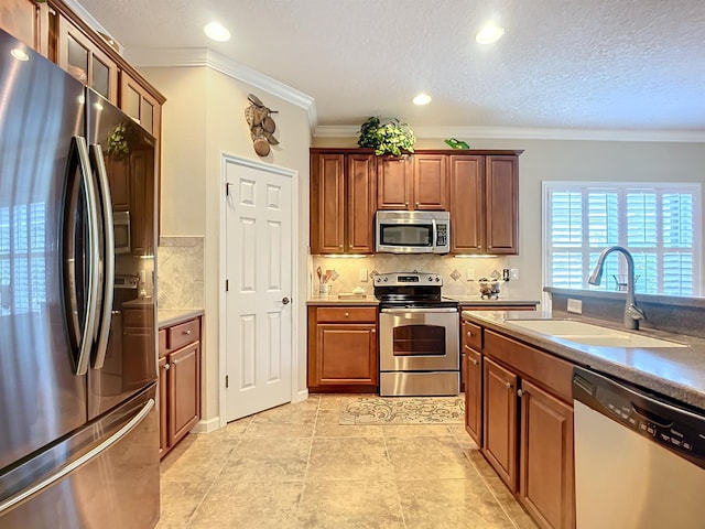 kitchen featuring decorative backsplash, ornamental molding, a textured ceiling, stainless steel appliances, and sink