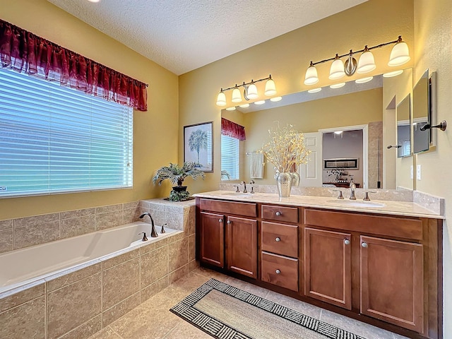 bathroom with vanity, a textured ceiling, a relaxing tiled tub, and tile patterned flooring