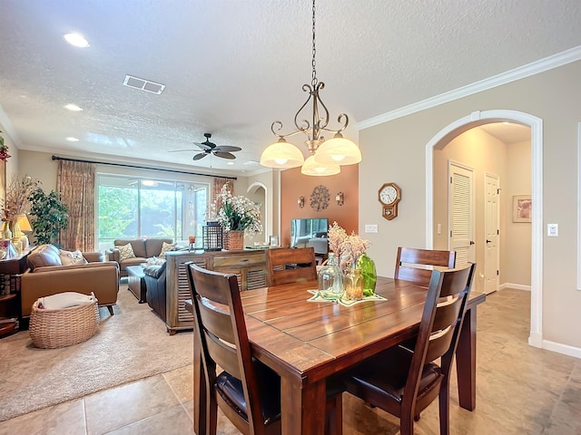 tiled dining room with ceiling fan with notable chandelier, a textured ceiling, and crown molding