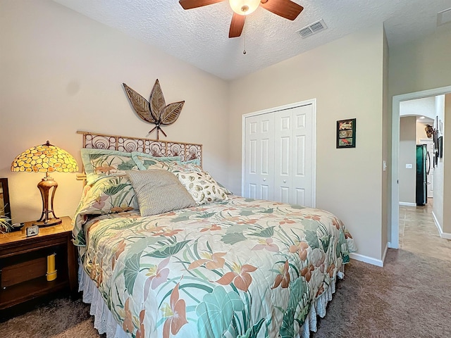 bedroom featuring black refrigerator, ceiling fan, a closet, and dark carpet