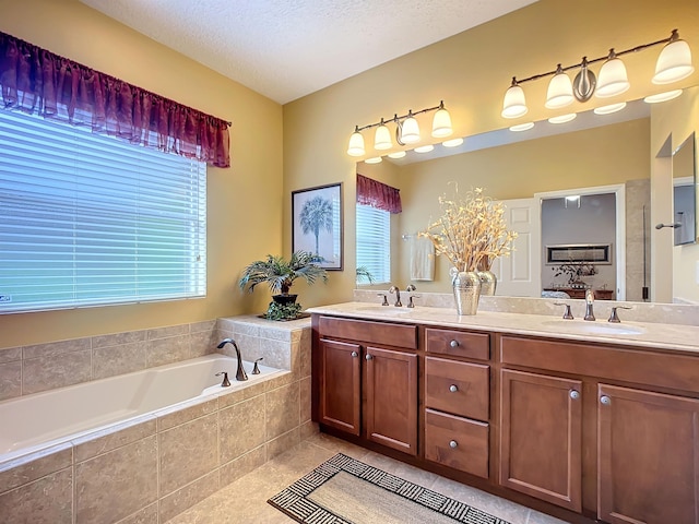 bathroom with tiled bath, tile patterned flooring, vanity, and a textured ceiling