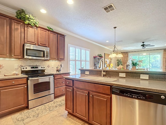 kitchen featuring appliances with stainless steel finishes, a wealth of natural light, ornamental molding, and sink