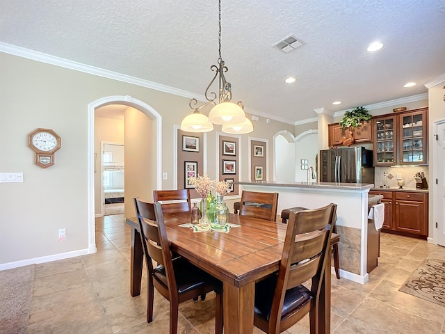 dining room with sink, light tile patterned floors, a textured ceiling, and ornamental molding