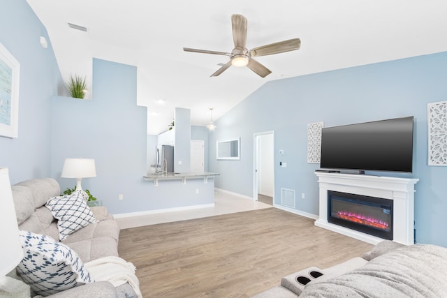 living room featuring ceiling fan, light hardwood / wood-style flooring, and vaulted ceiling