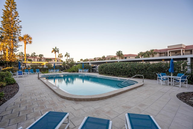 pool at dusk featuring a patio