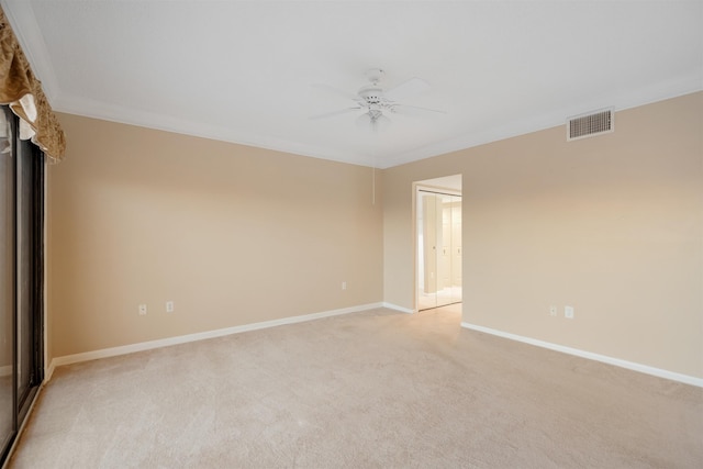 spare room with ceiling fan, crown molding, and light carpet