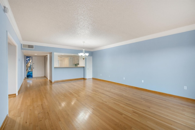 unfurnished living room with ornamental molding, light wood-type flooring, a textured ceiling, and a notable chandelier