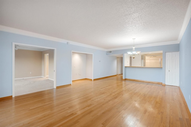 unfurnished living room with a chandelier, a textured ceiling, light wood-type flooring, and ornamental molding