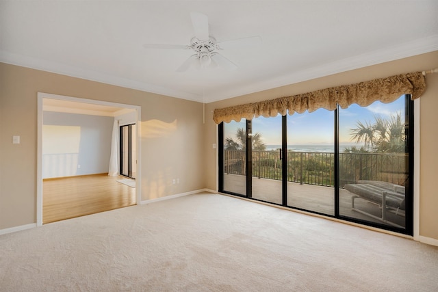 spare room featuring a water view, ceiling fan, carpet floors, and ornamental molding