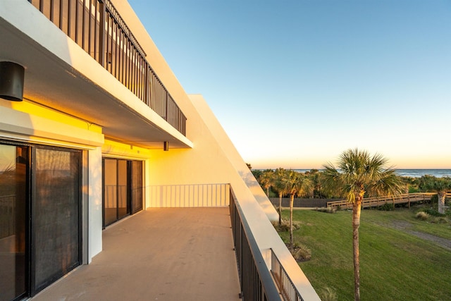 balcony at dusk featuring a water view