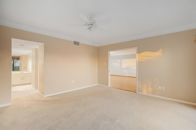 spare room featuring light carpet, crown molding, and ceiling fan