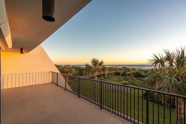 balcony at dusk featuring a water view