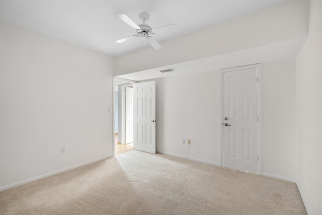 unfurnished room featuring ceiling fan, light carpet, and a textured ceiling