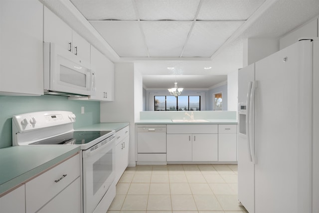 kitchen featuring white appliances, white cabinets, sink, light tile patterned floors, and a chandelier