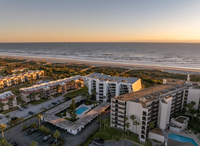 aerial view at dusk with a water view and a beach view