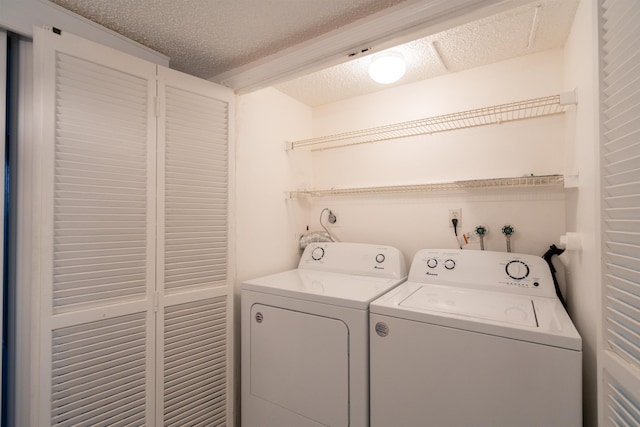 clothes washing area featuring a textured ceiling and washer and clothes dryer