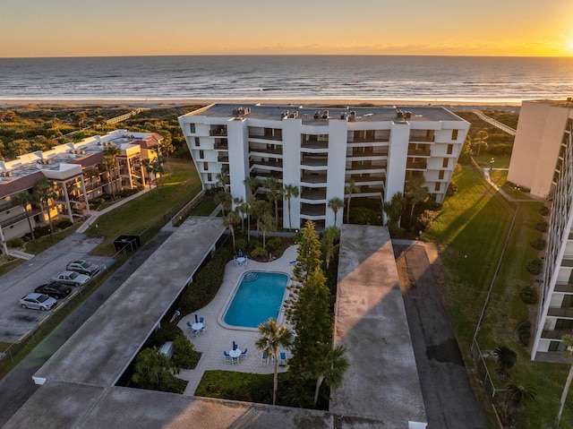 aerial view at dusk with a water view and a beach view