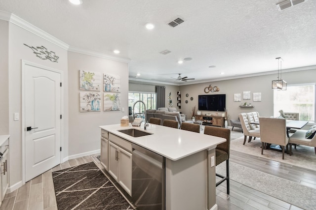 kitchen with dishwasher, a breakfast bar area, a kitchen island with sink, light countertops, and a sink