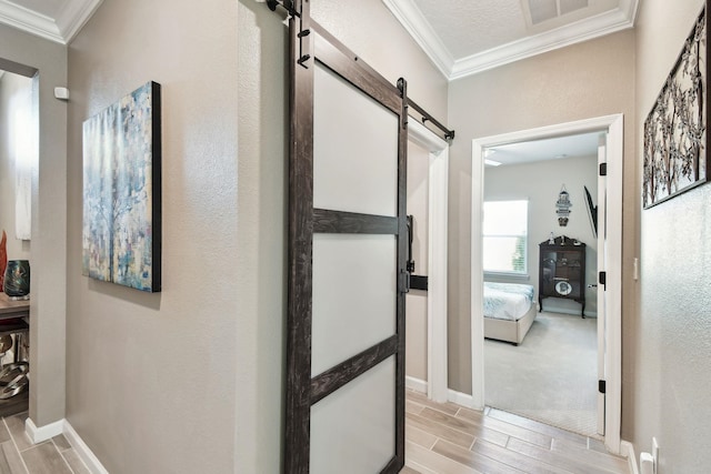 hallway with ornamental molding, a barn door, wood finish floors, and visible vents