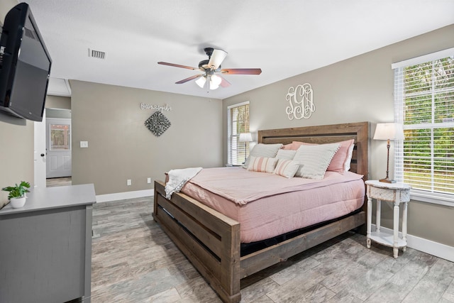 bedroom featuring light wood finished floors, baseboards, visible vents, and ceiling fan