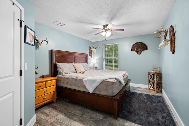 bedroom with a textured ceiling, ceiling fan, wood finished floors, visible vents, and baseboards