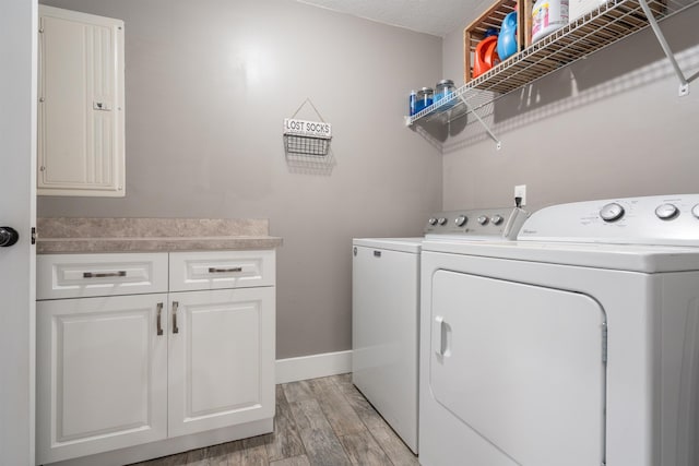 laundry area featuring cabinet space, washing machine and dryer, electric panel, and light wood-style flooring