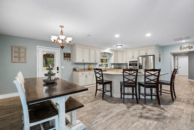 dining room featuring visible vents, light wood-style flooring, baseboards, and an inviting chandelier