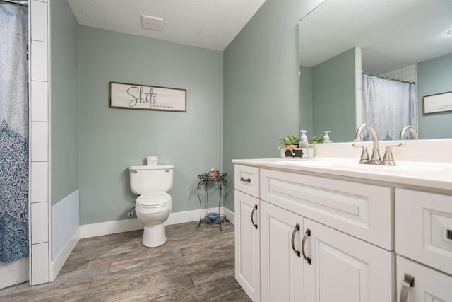 full bath featuring toilet, a textured ceiling, vanity, wood finished floors, and baseboards