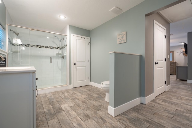 bathroom with wood finish floors, a shower stall, toilet, and baseboards