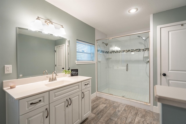 full bathroom with a shower stall, baseboards, wood finished floors, and vanity