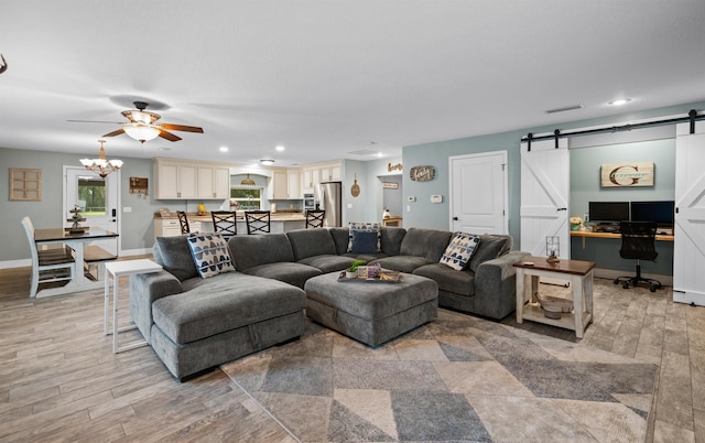 living area featuring baseboards, a barn door, visible vents, and light wood-style floors