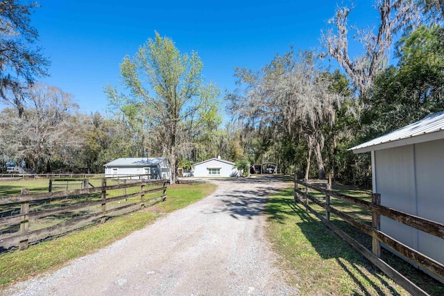 view of road with dirt driveway and a rural view