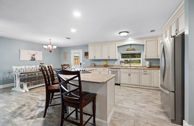 kitchen featuring a breakfast bar, a center island, light countertops, visible vents, and appliances with stainless steel finishes