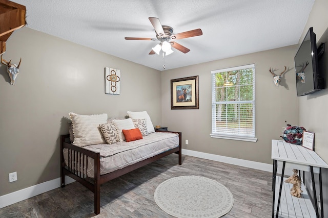 bedroom with a textured ceiling, baseboards, and wood finished floors