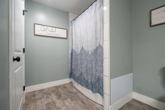 full bath with a textured ceiling, baseboards, and wood finished floors